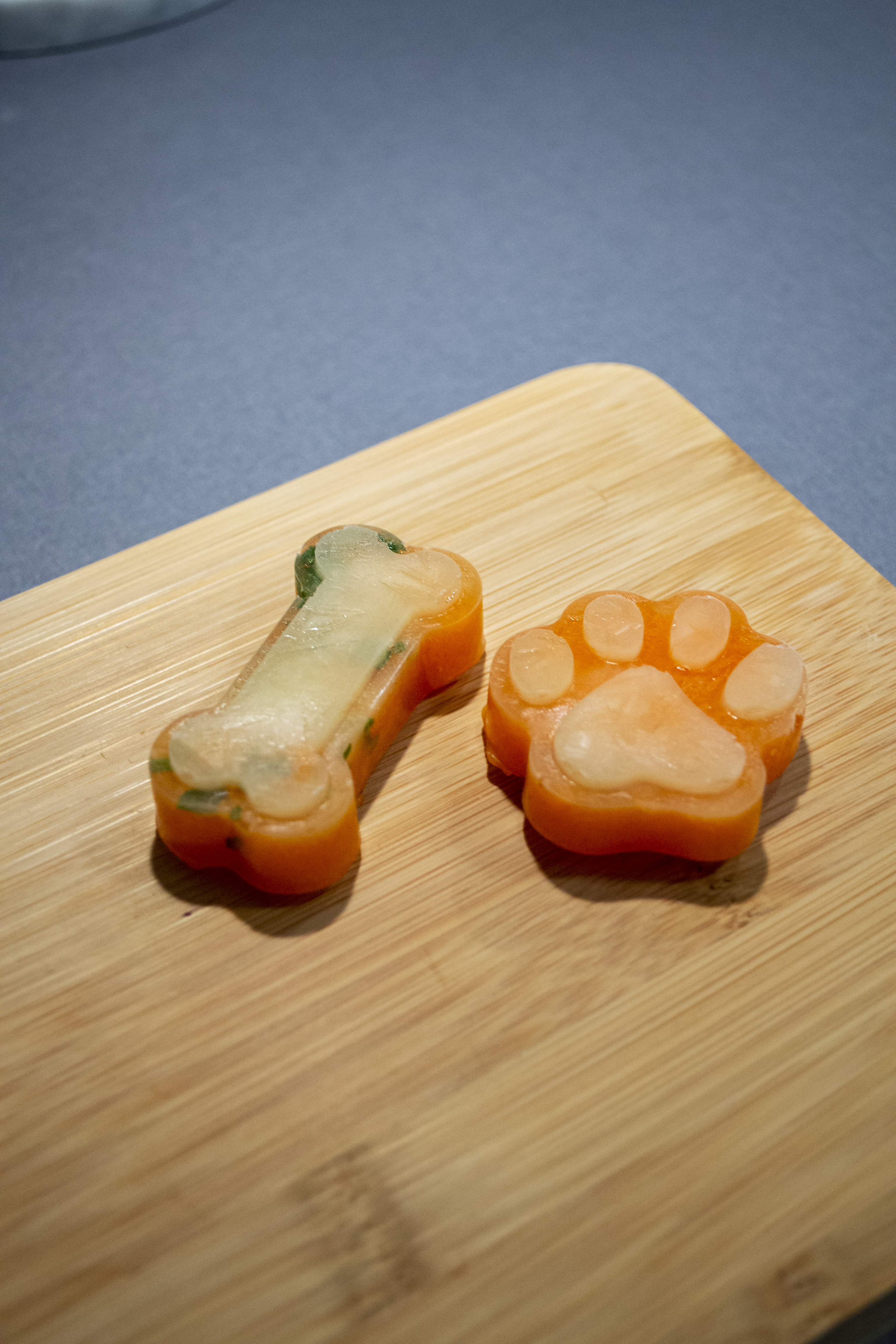 2 frozen dog treats laying on a cutting board.